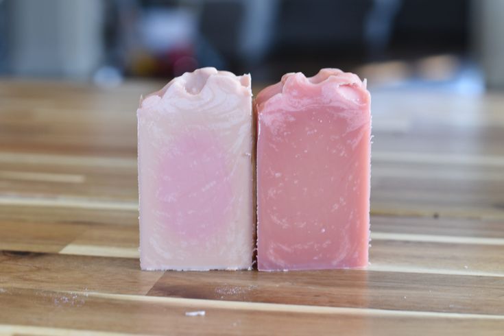 two bars of soap sitting on top of a wooden table