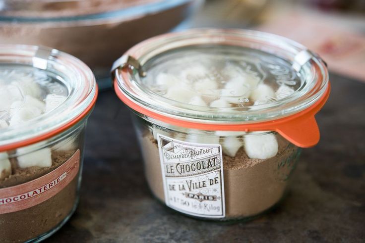 two jars filled with chocolate and marshmallows sitting on a counter top next to each other