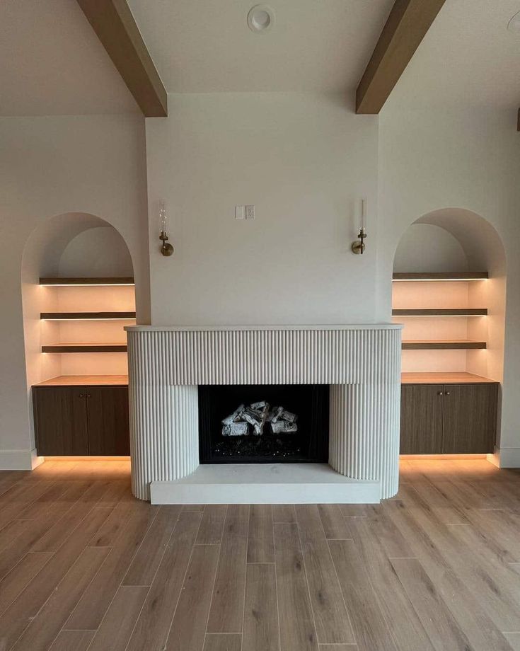 an empty living room with a fireplace and built in bookshelves on the wall