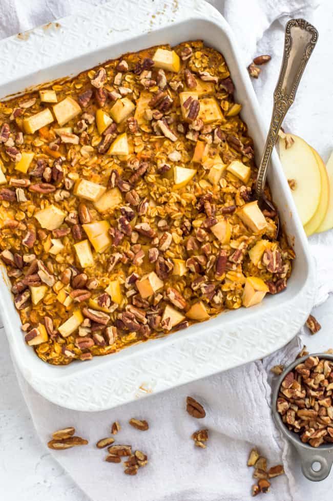 a casserole dish with apples and pecans in it on a white table