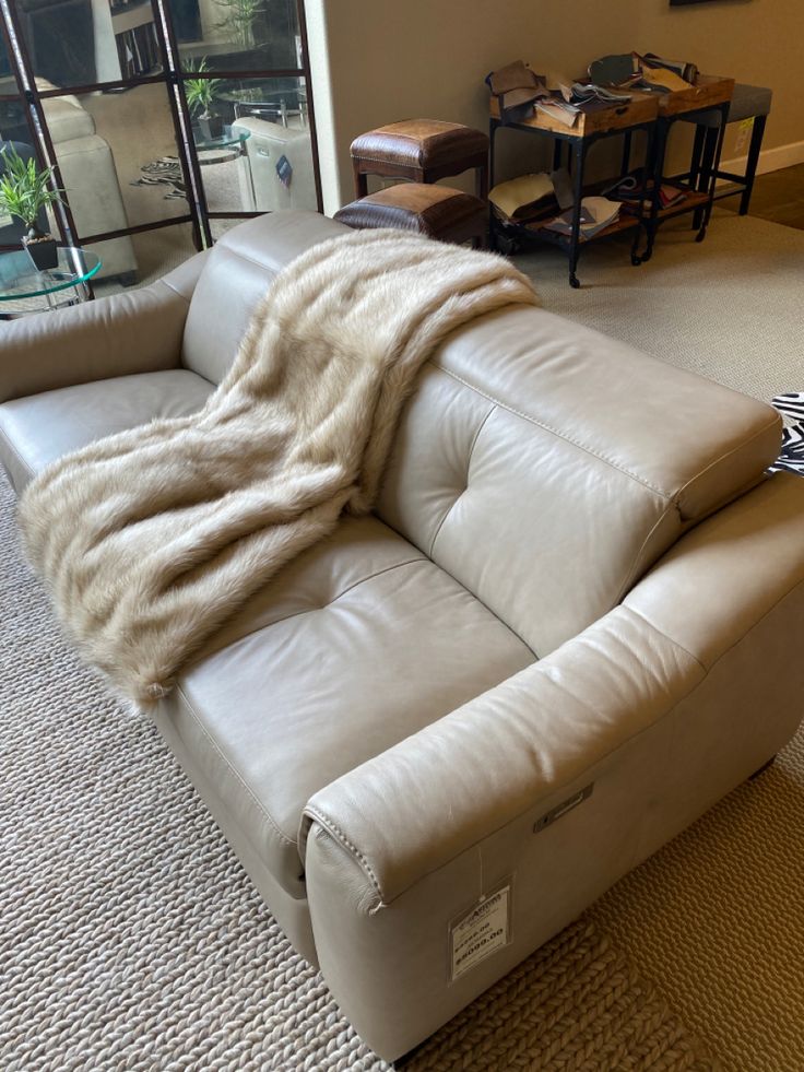 a white leather couch with a blanket on it