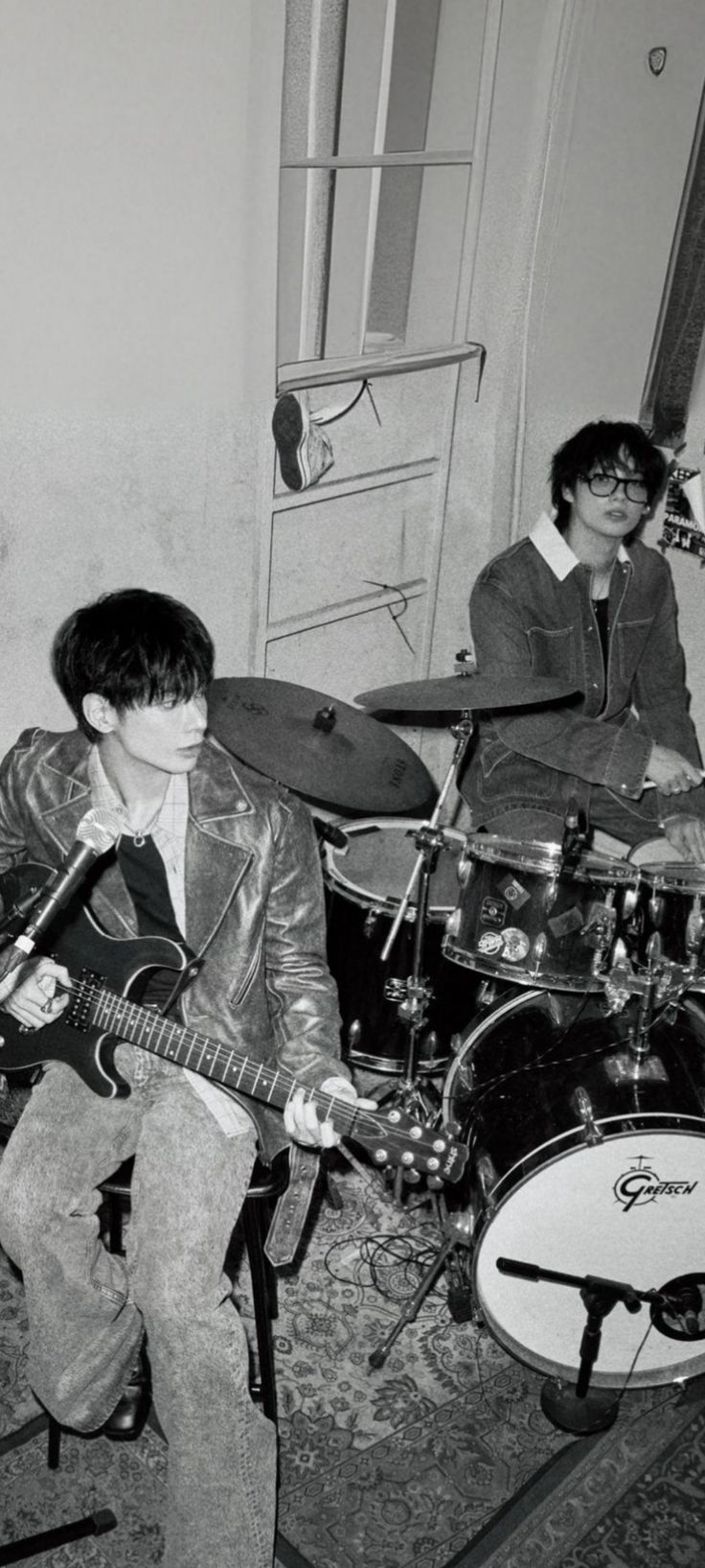 two young men are playing guitars and drums