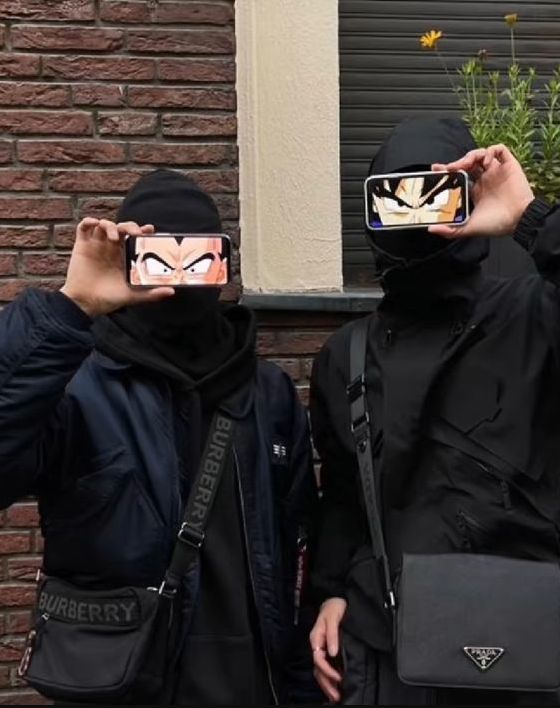 two people wearing masks and holding up cell phones