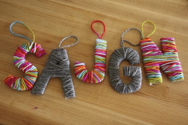 three yarn wrapped letters that spell out the word sale on a wooden table with twine spools