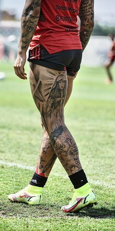 a man with tattoos on his legs walking across a field