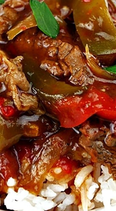 a close up of food on a plate with rice and vegetables in sauce, including peppers