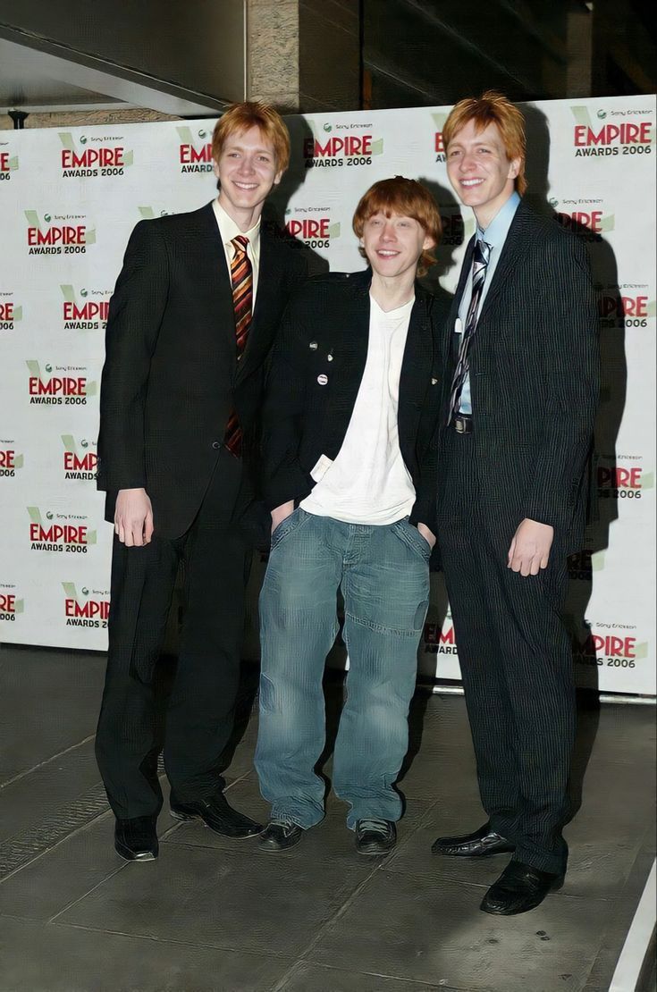 three young men standing next to each other in front of a white wall with the empire logo on it