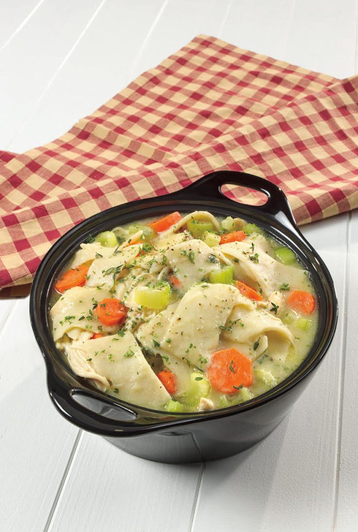 a bowl filled with chicken and dumplings on top of a table