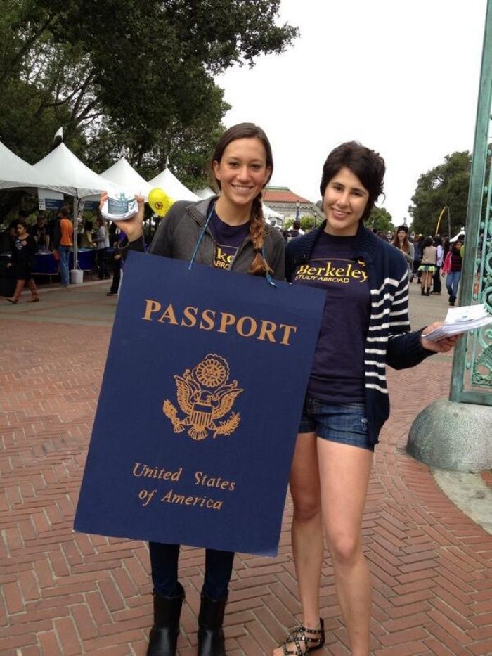 two women standing next to each other in front of a blue sign that says passport