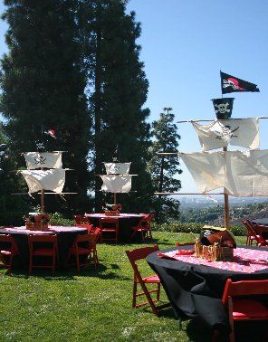 there are many tables and chairs set up with pirate flags on them in the grass