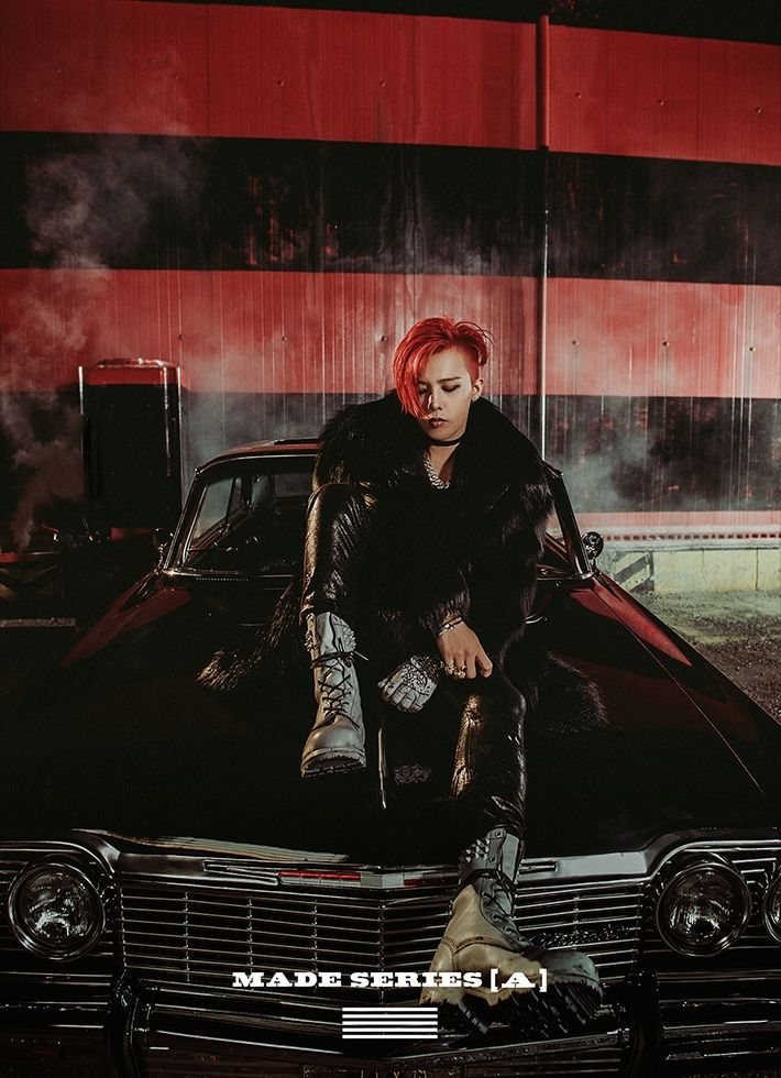 a man with red hair sitting on top of a car