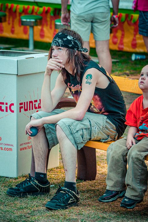 a young man sitting on top of a bench next to a little boy