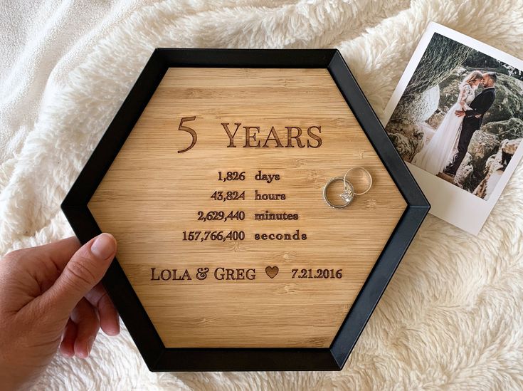 a couple's wedding rings are placed in front of a wooden frame with the date and year printed on it