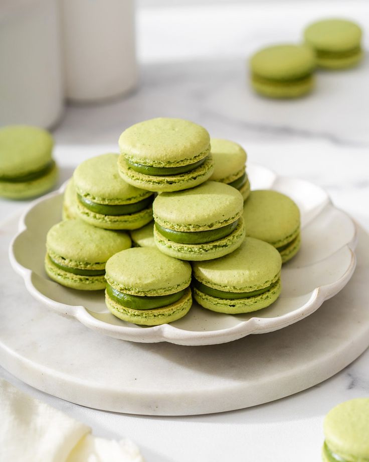 a white plate topped with green macaroons on top of a table