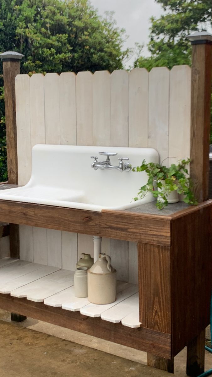 an outdoor sink and shelf with plants on it