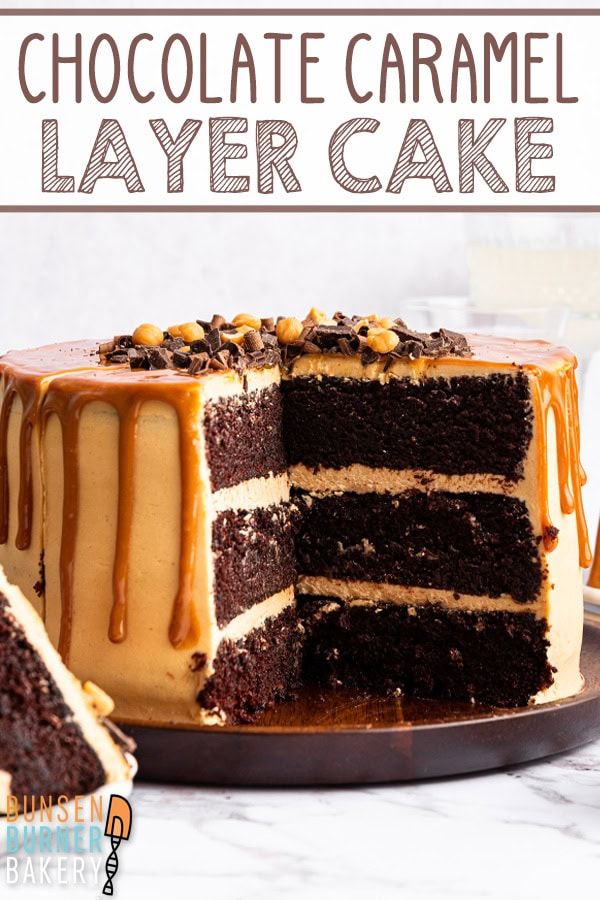 a chocolate caramel layer cake on a plate with one slice cut from the cake