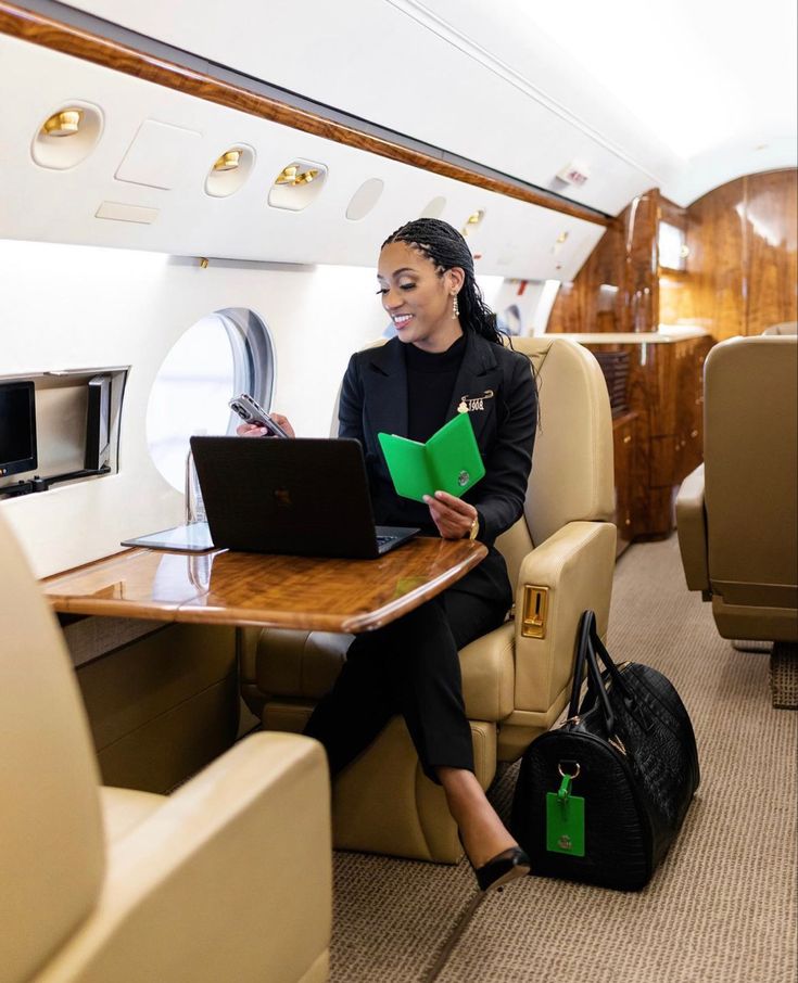 a woman is sitting in an airplane with her laptop and folders on the table