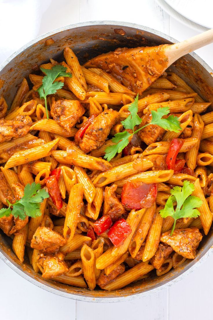 a skillet filled with pasta and meat covered in sauce, garnished with parsley