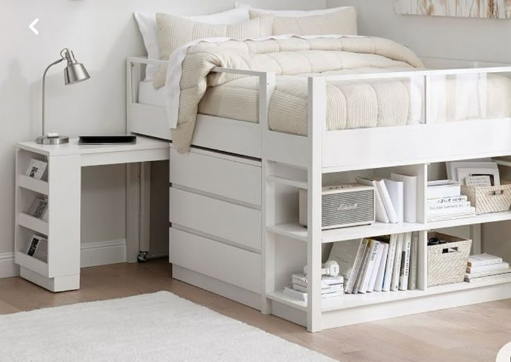 a white bed sitting next to a desk with a book shelf on top of it