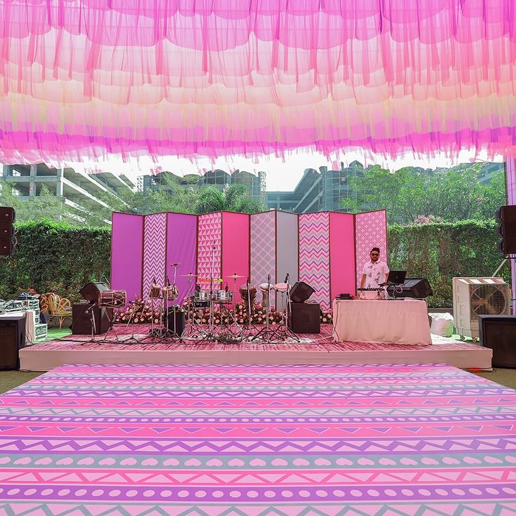 a stage set up with pink and purple curtains on the wall, decorated with decorative items