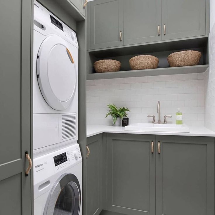 a washer and dryer in a small laundry room with gray cabinets, white counter tops and marble flooring