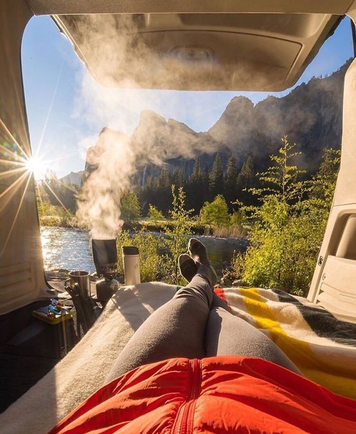 a person is sitting in the back of a van with their feet up on the bed