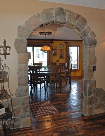 an archway leads into the dining room and living room, which is decorated in natural stone