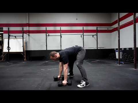 a man is bent over with two dumbbells on his feet in a gym