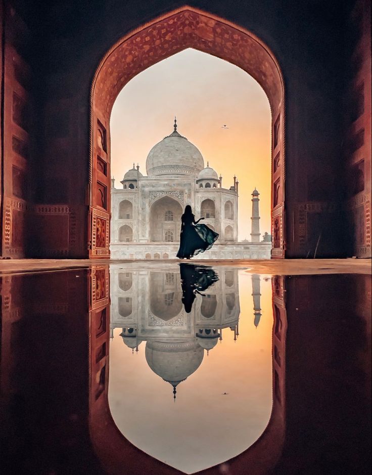 a person standing in front of a building with a reflection on the water