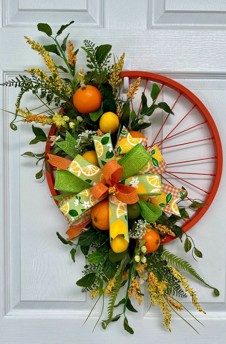 a wreath with oranges and green leaves on the front door