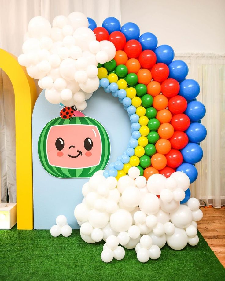 there is a balloon arch with balloons on it and a rainbow in the background,