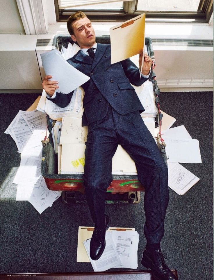 a man in a suit sitting on top of a pile of papers