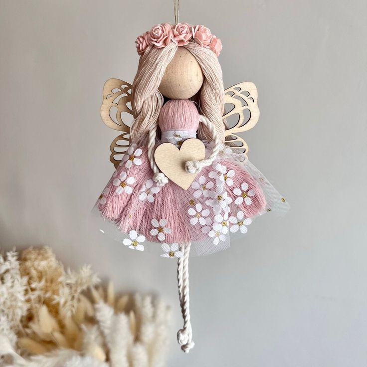 a pink and white fairy ornament hanging from a string