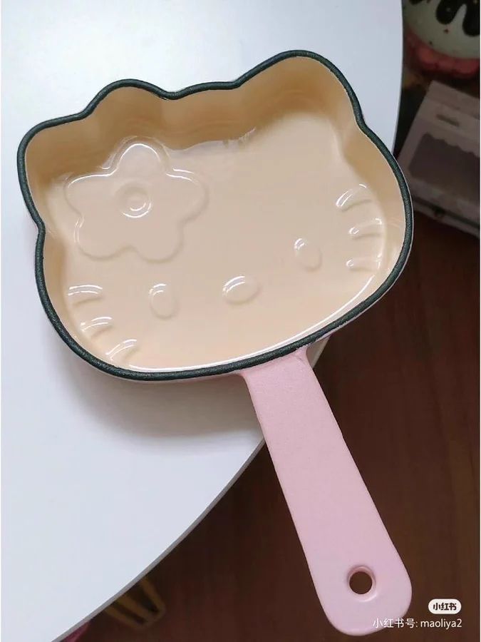 a cake pan with a hello kitty design on the side and a pink spatula