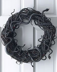 a wreath made out of wire and snakes hanging from it's sides on a door