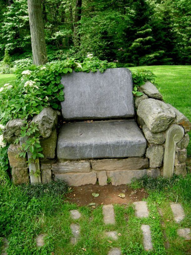 a stone bench sitting in the middle of a lush green park