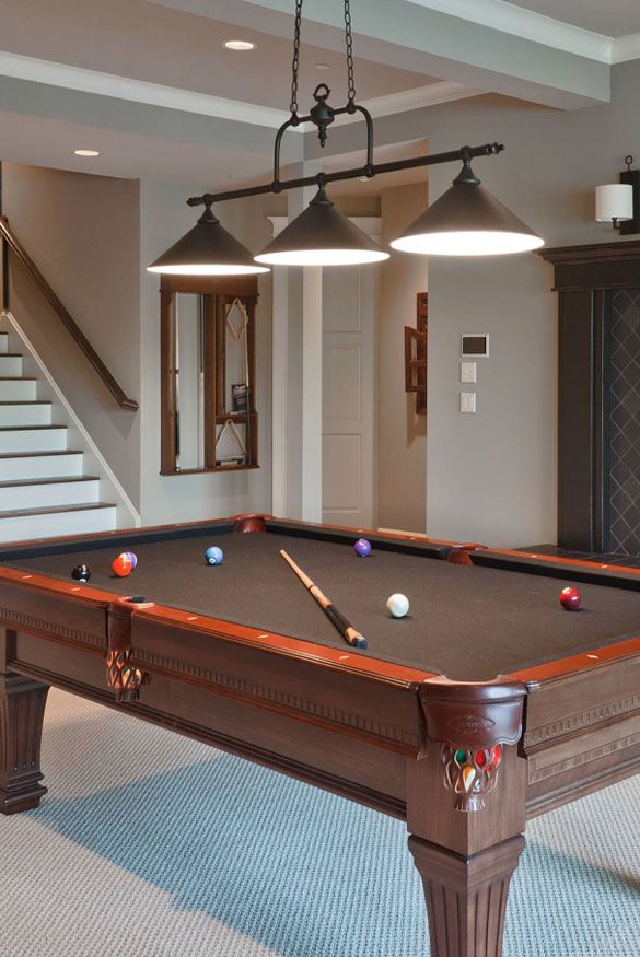 a pool table in the middle of a room with two lights hanging from it's ceiling