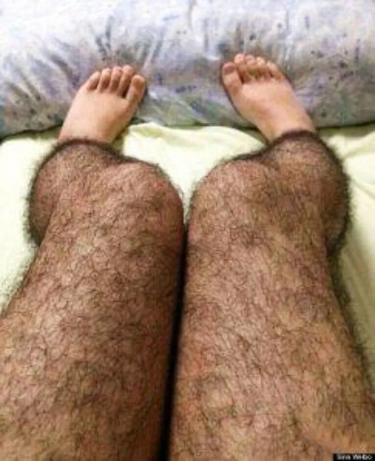 a man laying on top of a bed with his legs spread out and hairy pants