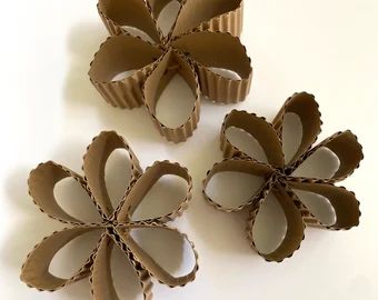 three brown paper flowers sitting on top of a white table next to cupcake liners