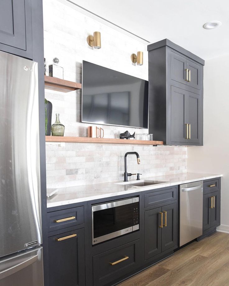 a kitchen with gray cabinets and gold pulls on the doors is pictured in this image