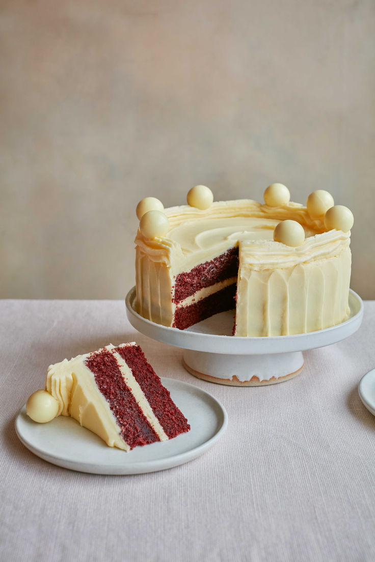 a slice of red velvet cake on a plate next to the rest of the cake