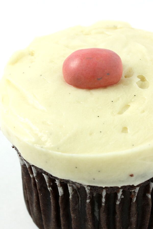 a cupcake with white frosting and a red candy on top