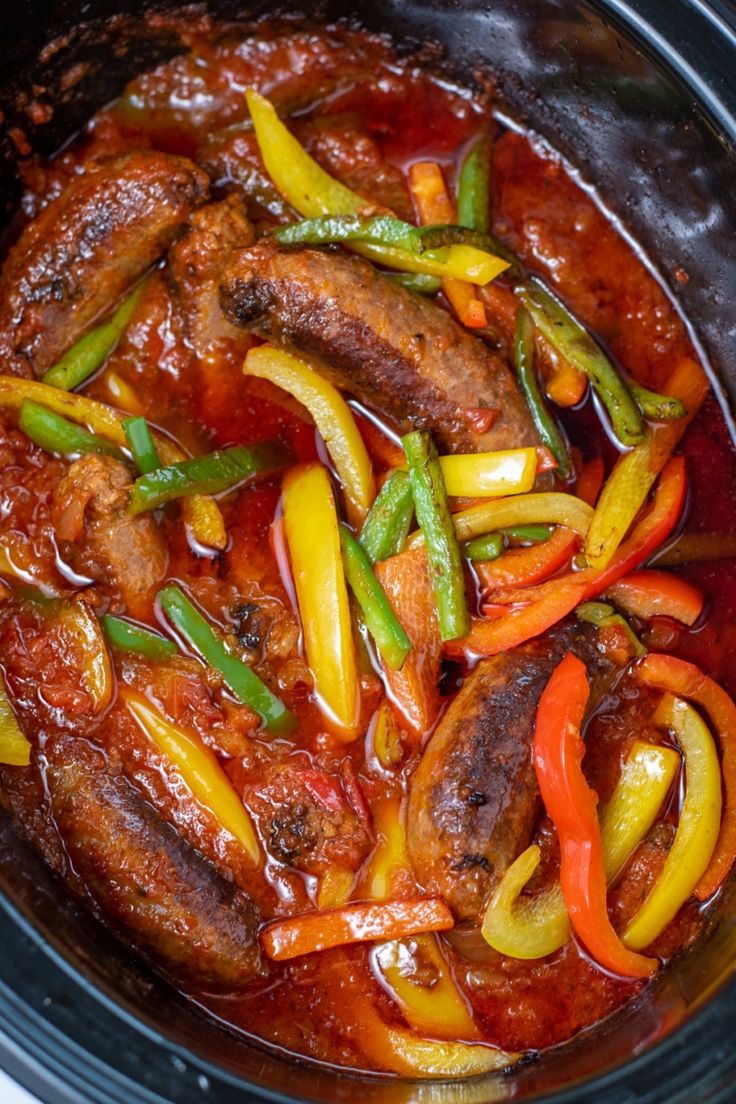 a slow cooker filled with meat, peppers and green beans on top of it