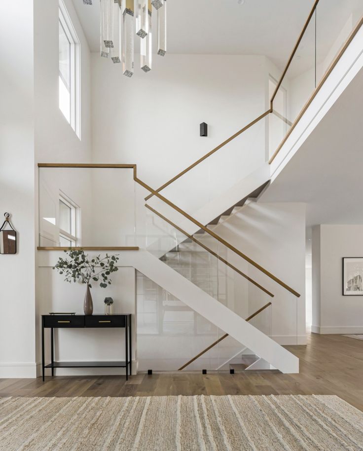 a white staircase in a house with wood flooring and chandelier hanging from the ceiling