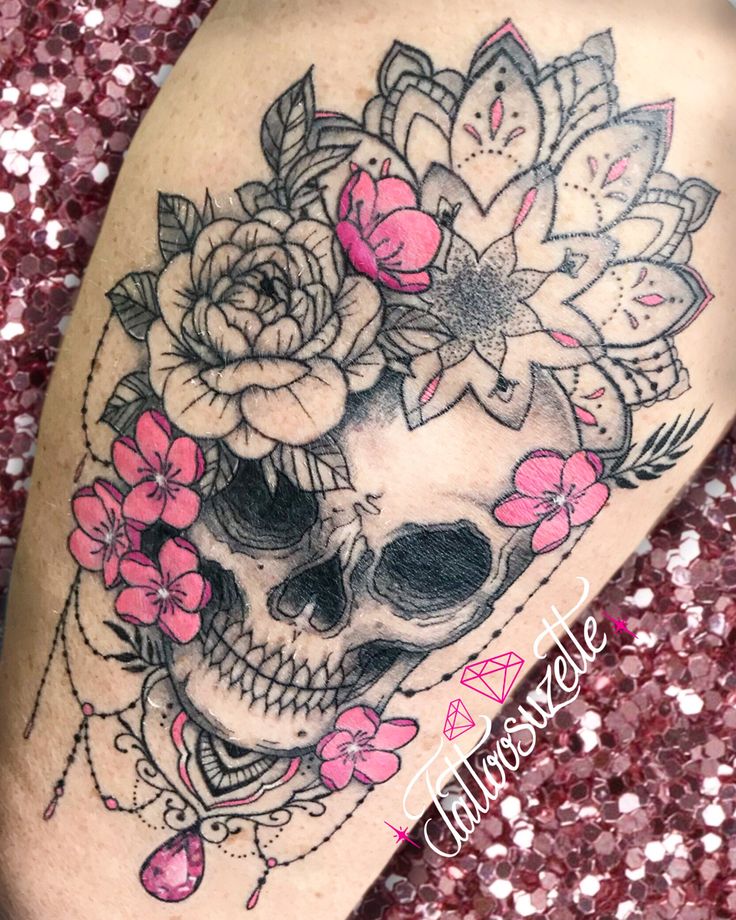 a woman's thigh with a skull and flowers on it