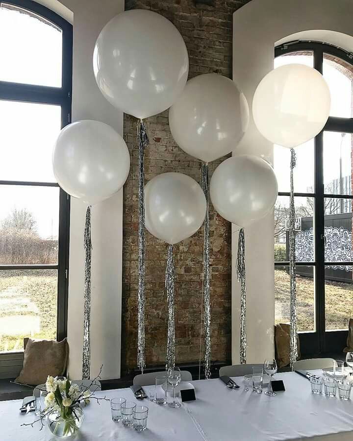 white balloons are hanging from the ceiling above a table with place settings for four people