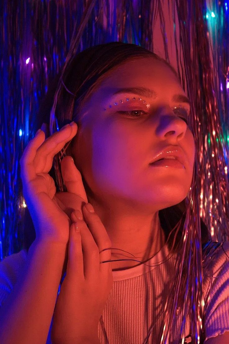 a woman is talking on her cell phone in front of some lights and streamers