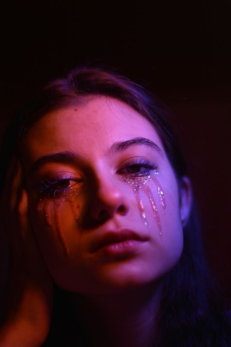 a woman with tears on her face in the dark