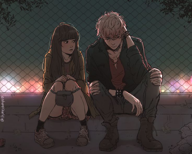 two people sitting on the ground in front of a fence