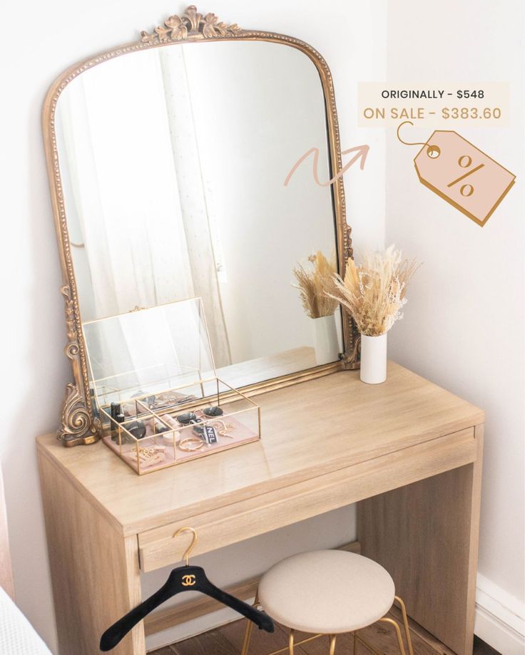 a mirror sitting on top of a wooden desk next to a white stool with a plant in it